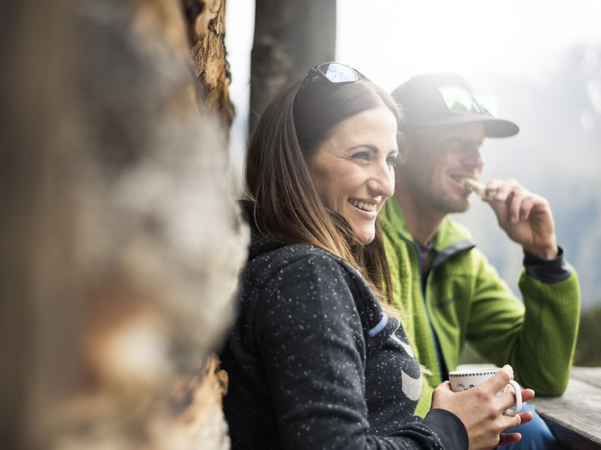 Aktivtipps für Ihren Urlaub im Stubaital Lächendes Paar trinkt und isst draußen an einem Holztisch