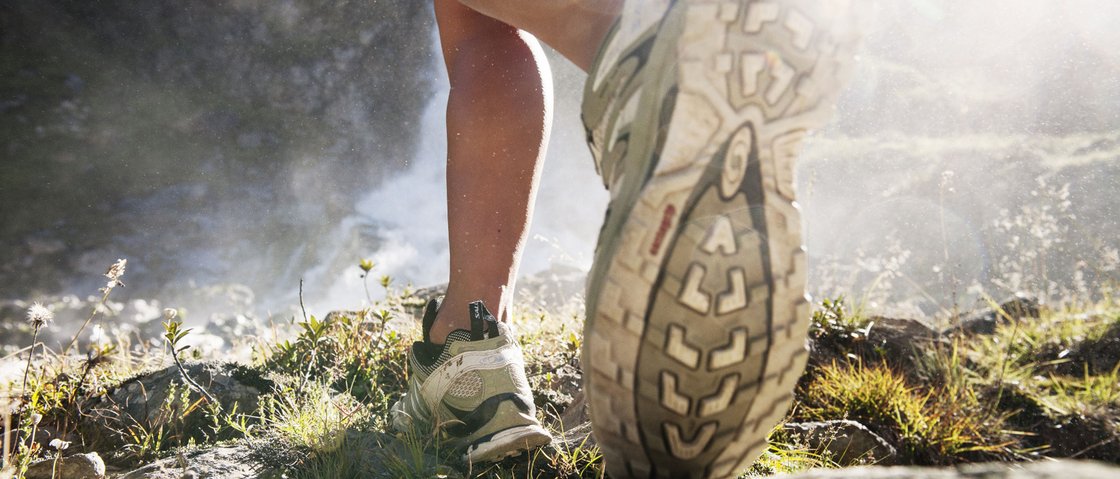 Bereit für Ihren Urlaub im Stubaital im Sommer? Nahaufnahme eines Wanderers, der über felsigen Boden mit Laufschuhen geht