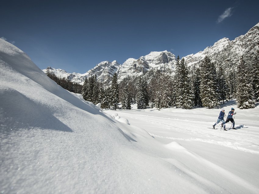 Sanft und genüsslich: Langlauf im Stubaital Langläufer im verschneiten Wald mit Berglandschaft und klarem Himmel