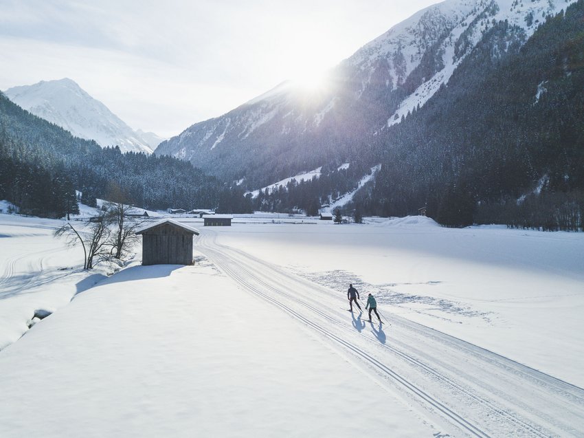 That little extra on your ski holiday in Stubaital Two cross-country skiers in snowy valley with mountains and sun in background