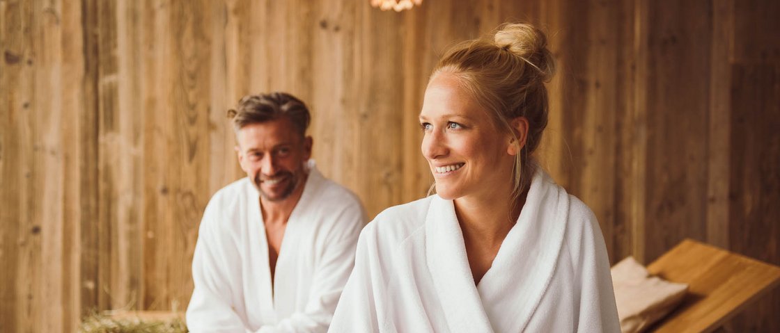 Rejuvenation at our 4-star wellness hotel in Tyrol A man and woman in white robes relaxing in a rustic spa room