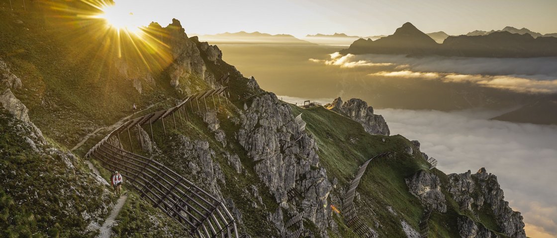 Love for nature at our hiking hotel in Stubaital Sunrise over mountain trail with protective wooden fences and a hiker