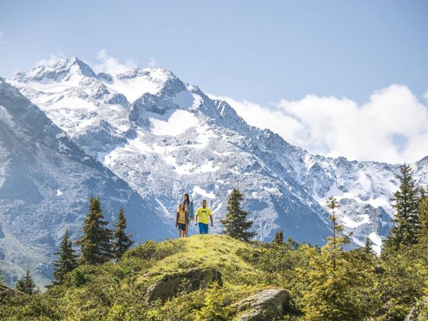 Love for nature at our hiking hotel in Stubaital Two hikers on a green hill with snow-covered mountains in the background