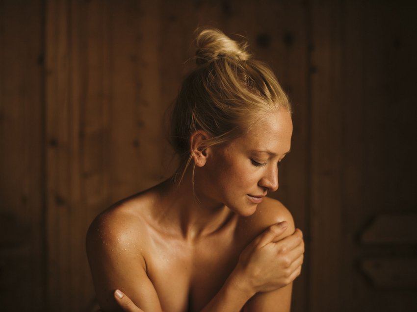 Unwind at our spa hotel in Stubaital Woman relaxing in sauna with eyes closed and hand on shoulder