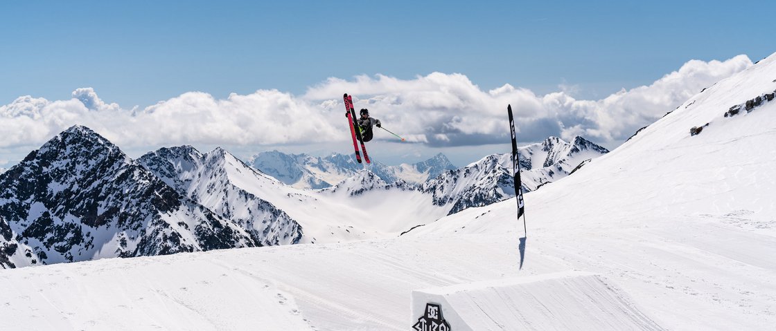 Dreaming of skiing? Head to our ski hotel in Stubaital! Skier jumping in snowy mountains under clear blue sky