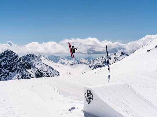 Dreaming of skiing? Head to our ski hotel in Stubaital! Skier jumping in snowy mountains under clear blue sky