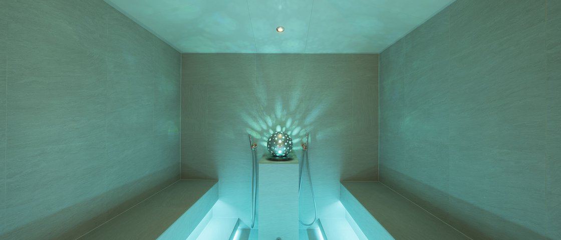 Rejuvenation at our 4-star wellness hotel in Tyrol Modern steam room with blue lighting and benches on both sides