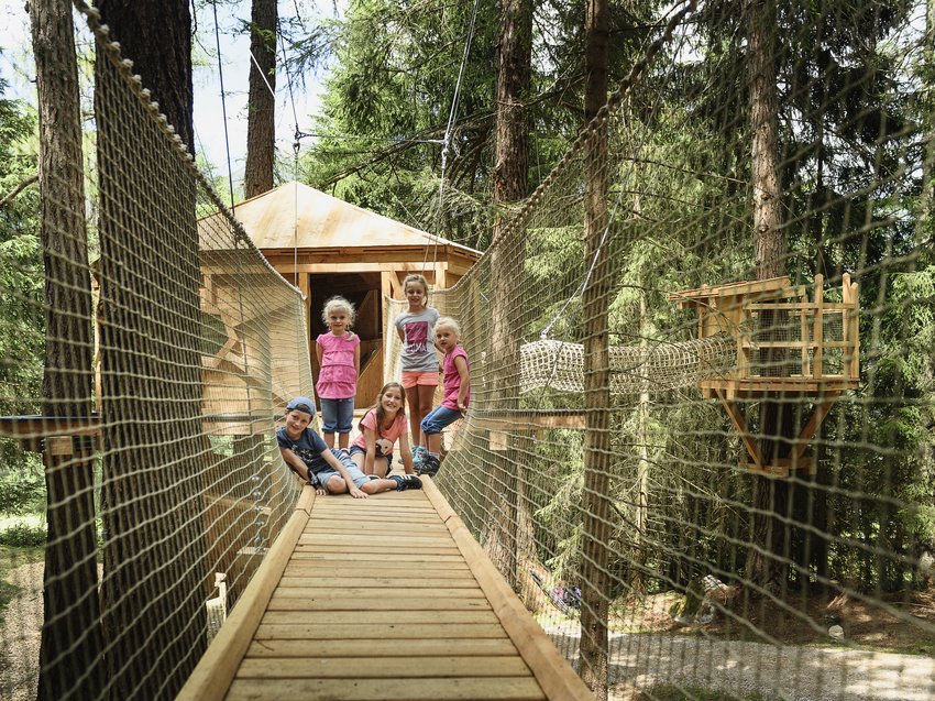 Die Stubai Super Card – immer an Ihrer Seite Kinder auf einer Hängebrücke vor einem Baumhaus im Wald