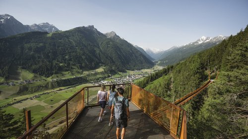 The best hotel offers in Tyrol Three hikers on viewing platform overlooking bridge and green valley