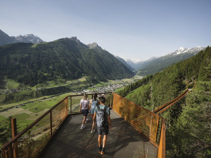 Aktivtipps für Ihren Urlaub im Stubaital Drei Wanderer auf Aussichtsplattform mit Blick auf Brücke und grünes Tal