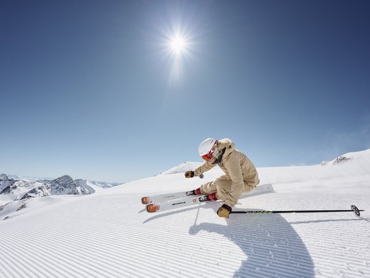 Dreaming of skiing? Head to our ski hotel in Stubaital! Skier in beige jacket skiing on freshly groomed snow under bright sun
